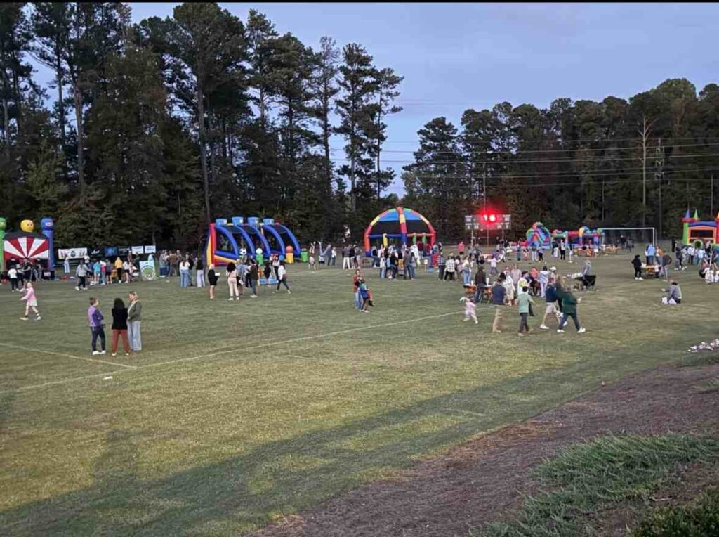 Multiple colorful bounce houses and inflatables arranged at an outdoor Atlanta community gathering